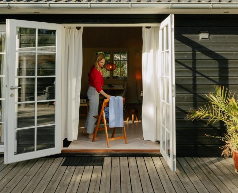 Frau nimmt Handtuch von Stuhl im Ferienhaus in Nordseeland, Dänemark