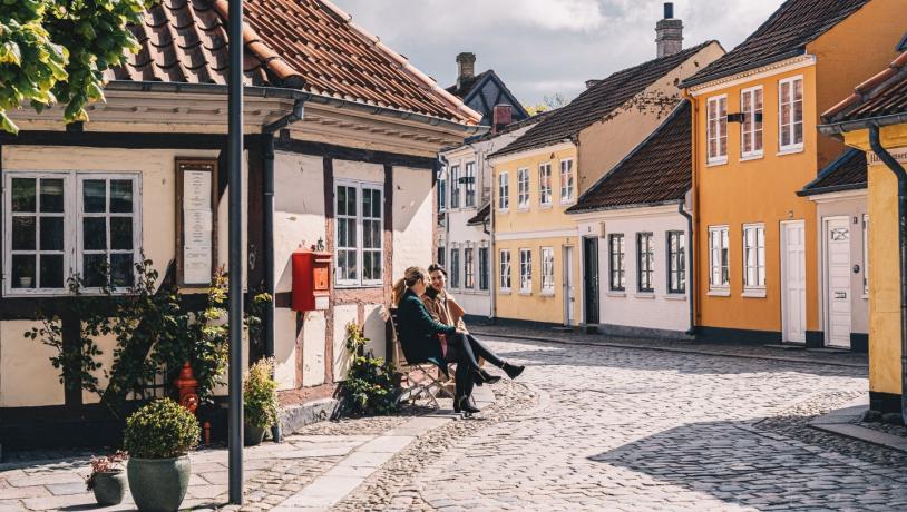 Zwei Freunde auf einer Bank in der Altstadt von Odense auf der dänischen Ostseeinsel Fünen