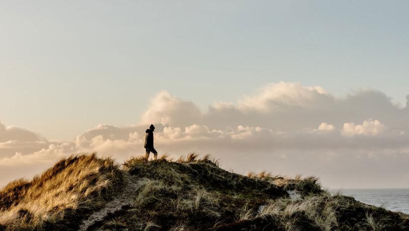 Boy walking on a windy sand dune in Klitmoeller, Thy National Park