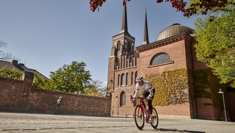 Bild von einem Rennradfahrer, der vorbei Roskilde Dom fährt