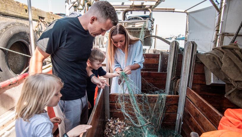 Bild von einer Familie auf den Kutter, die Muscheln sucht