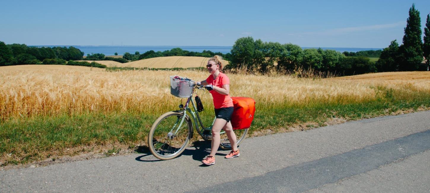 Frau schiebt ihr Fahrrad auf einem Radurlaub auf dem Dänischen Ostseeradweg