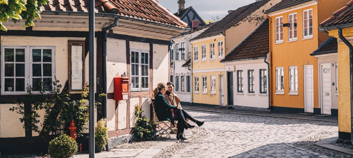 Zwei Freunde auf einer Bank in der Altstadt von Odense auf der dänischen Ostseeinsel Fünen
