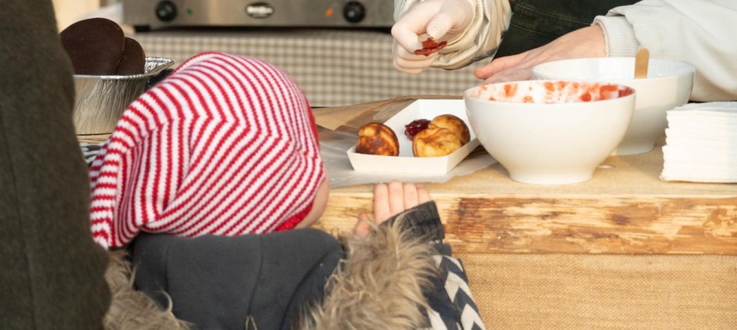 A child buying æbleskiver at a stall at the Open Air Museum in North Sealand.