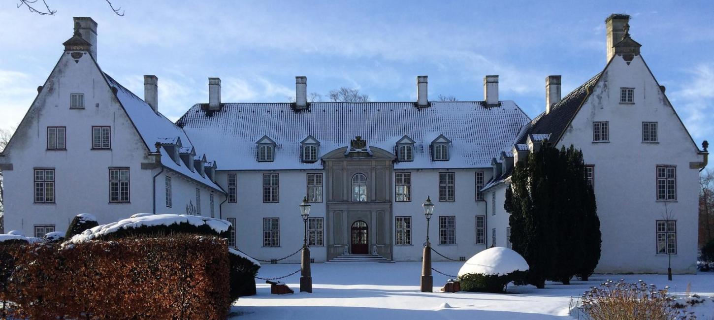 Bild vom Schloss Schackenborg in der Winterzeit, das von Schnee bedeckt ist.