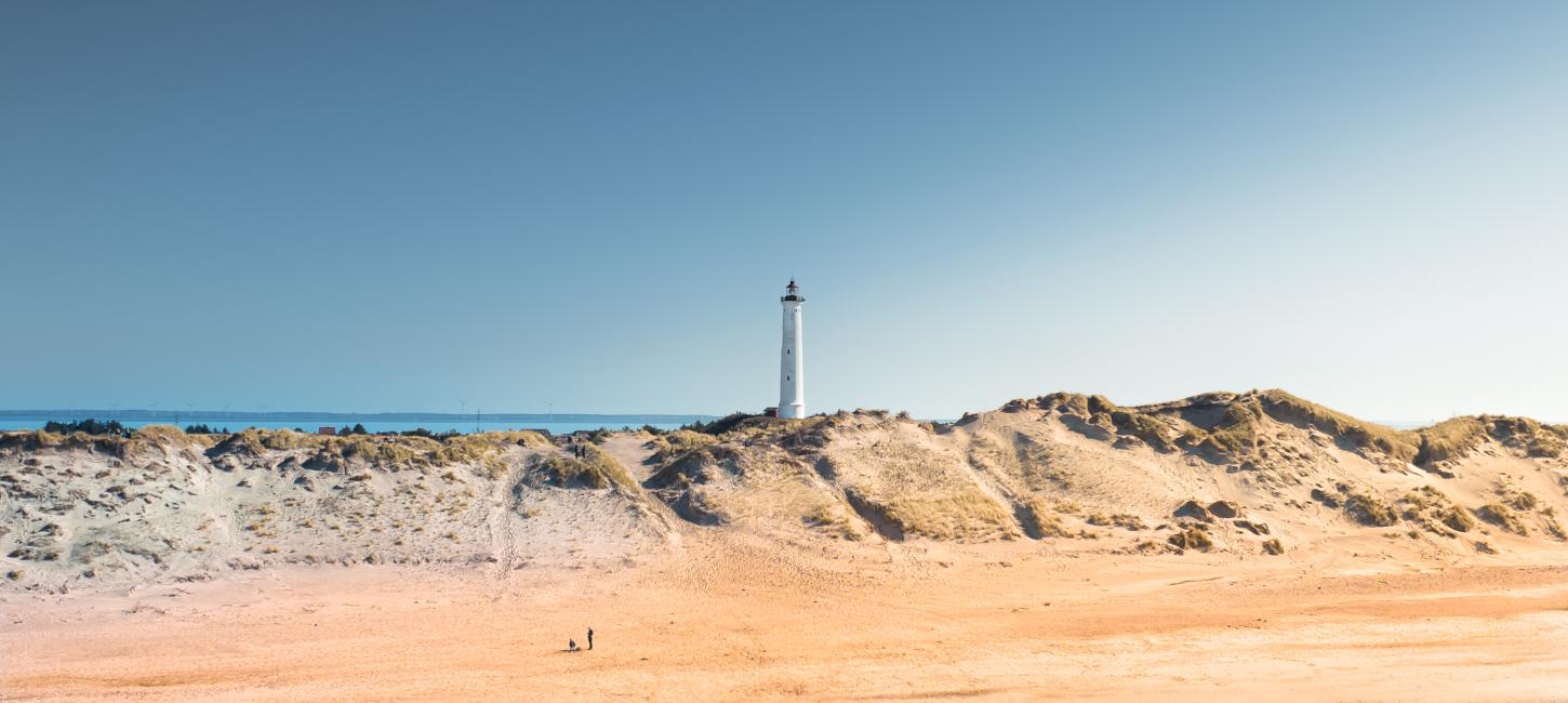 Bild vom Lyngvig Leuchtturm mit einem Strand und Wasser im Vordergrund