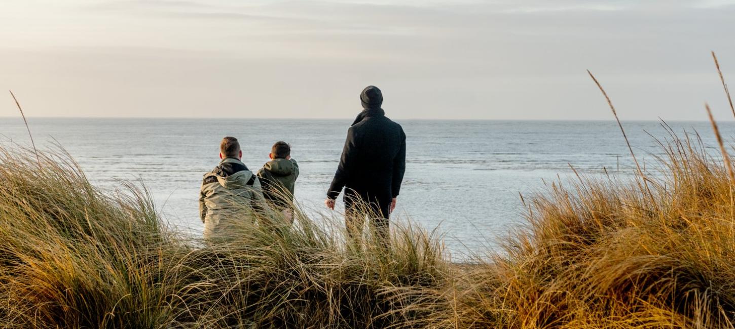 Familie kijkt naar de zee bij Blåvand strand, West-Jutland