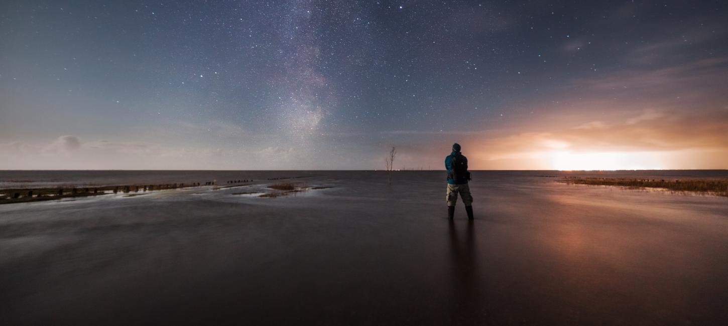 Ein Bild von einem Mand, der am Strand unter einem Dark Sky steht