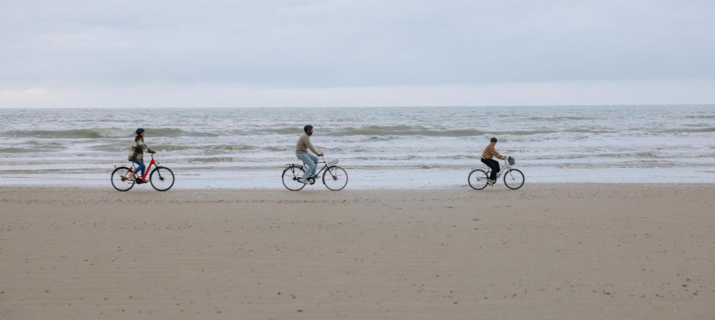 Familie fährt Fahrrad am Strand der dänischen Nordseeküste