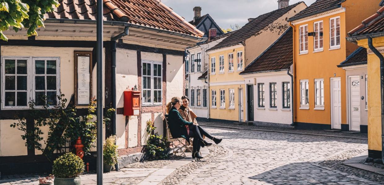 Zwei Freunde auf einer Bank in der Altstadt von Odense auf der dänischen Ostseeinsel Fünen