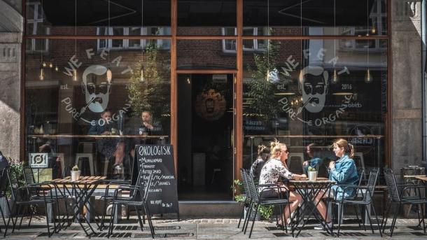 People eating on the street outside vegetarian restaurant We Feat in Aalborg, Denmark 