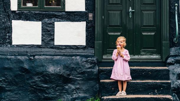 A little child eats ice cream on the stairs in front of a house, Ebeltoft