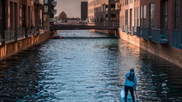 A man paddleboarding in a canal in Copenhagen, Denmark