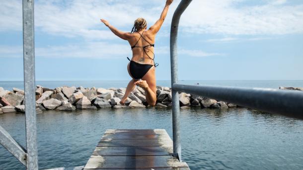 Person jumping in water at Svaneke harbour in Bornholm