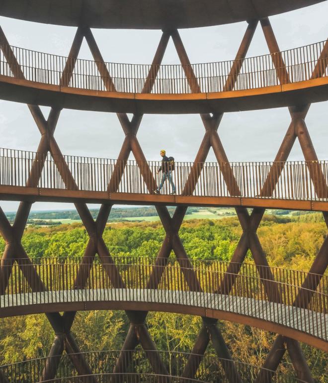 A man walks up Camp Adventure, a forest tower in Denmark.