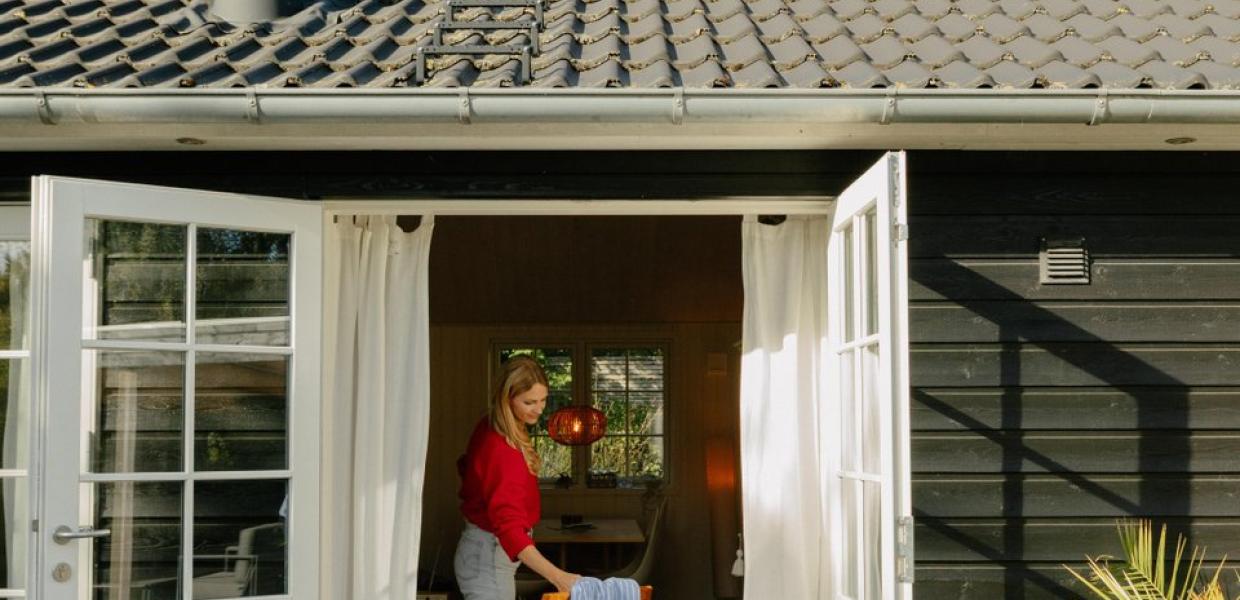 Frau nimmt Handtuch von Stuhl im Ferienhaus in Nordseeland, Dänemark