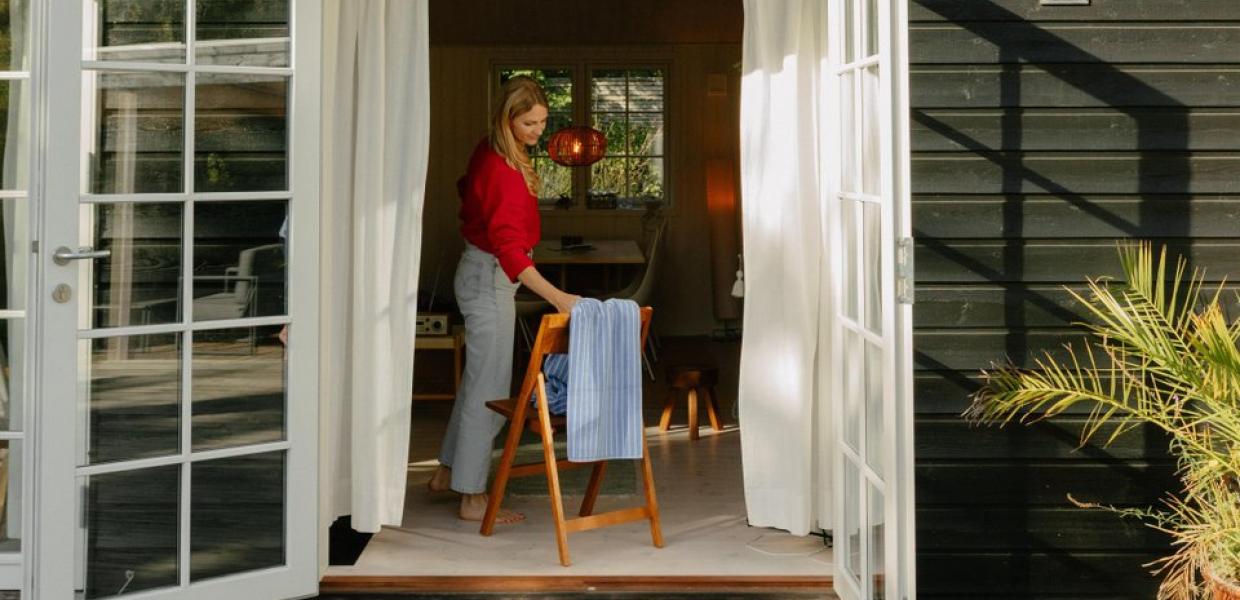 Frau nimmt Handtuch von Stuhl im Ferienhaus in Nordseeland, Dänemark