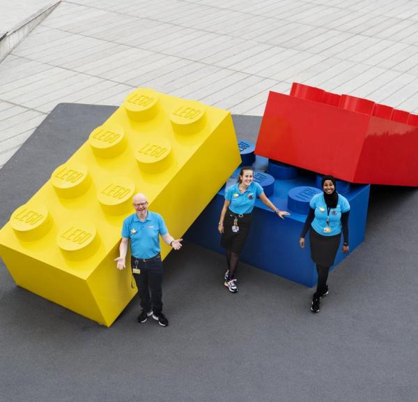 Lego House, Billund: Mitarbeiter stehen vor sehr großen Legosteinen. 