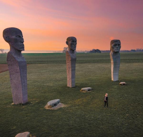 Person looking at stone sculptures Dodekalitten during sunset on Lolland-Falster, Denmark