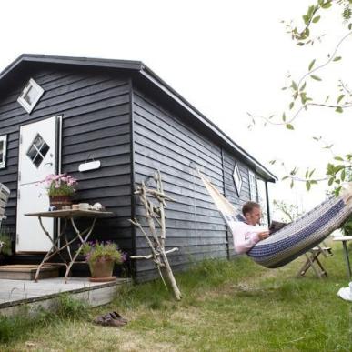 Mann entspannt in Hängematte vor einem Ferienhaus in Dänemark