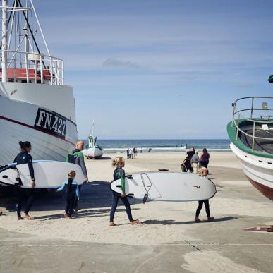 Familie mit Surfbrettern am Strand von Løkken in Nordjütland