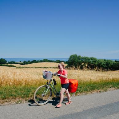 Frau schiebt ihr Fahrrad auf einem Radurlaub auf dem Dänischen Ostseeradweg