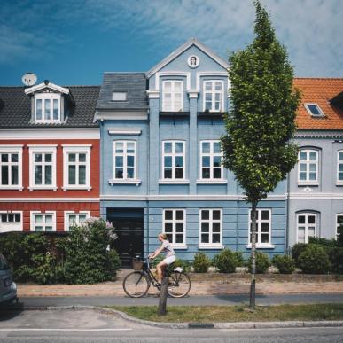 Fahrradfahrerin vor bunten Häusern in Odense auf der dänischen Ostseeinsel Fünen