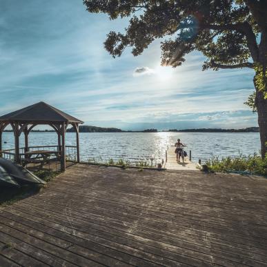 Fahrradfahrerin steht am See im Maribo Naturpark, Lolland-Falster