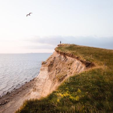Person standing at the Limfjord on a cliff, Denmark