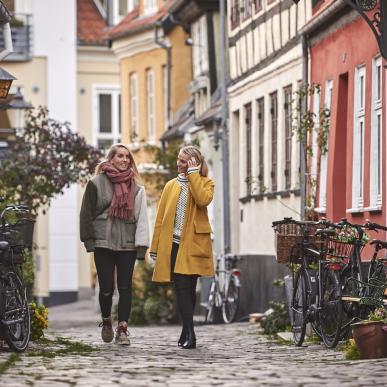 To kvinner går i Aalborgs gater på høsten