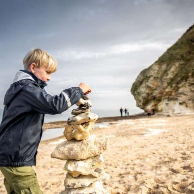 Child playing on the beach with stones in Dnemark,  Bulbjerg