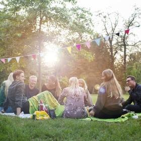 Freunde sitzen zusammen bei einem Picknick im Kopenhagener Park Frederiksberg Have
