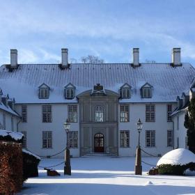 Bild vom Schloss Schackenborg in der Winterzeit, das von Schnee bedeckt ist. 
