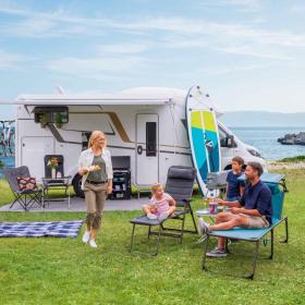Familie sitzt vor Campingvan in Dänemark