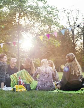 Freunde sitzen zusammen bei einem Picknick im Kopenhagener Park Frederiksberg Have