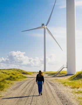 Woman walking towards a windmill at Hvide Sande, Jutland