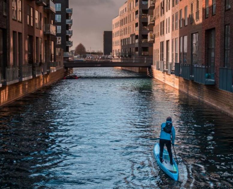 A man paddleboarding in a canal in Copenhagen, Denmark