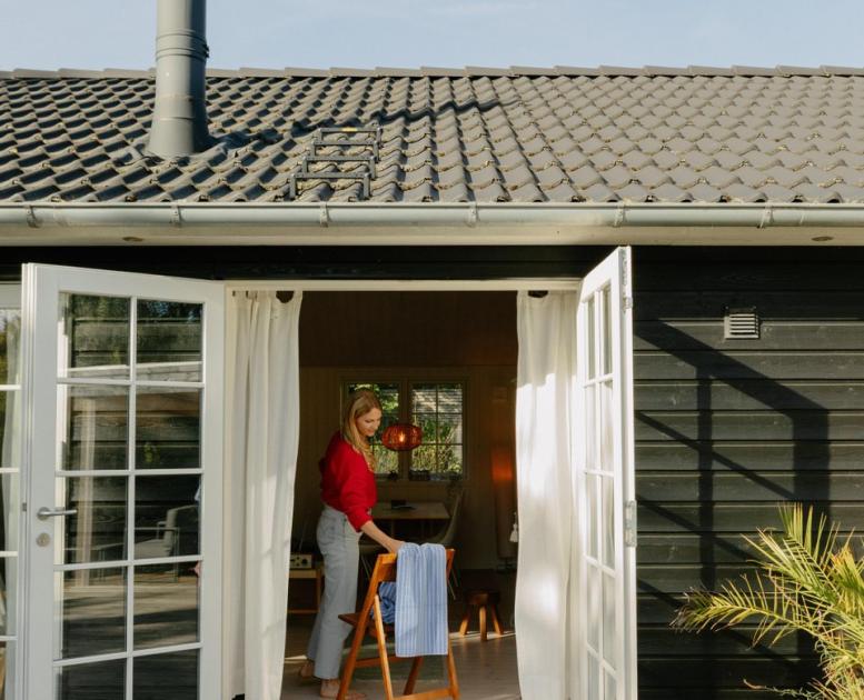 Frau nimmt Handtuch von Stuhl im Ferienhaus in Nordseeland, Dänemark