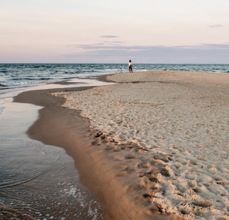 Kvinne som står på stranden på Grenen i Skagen i Danmark