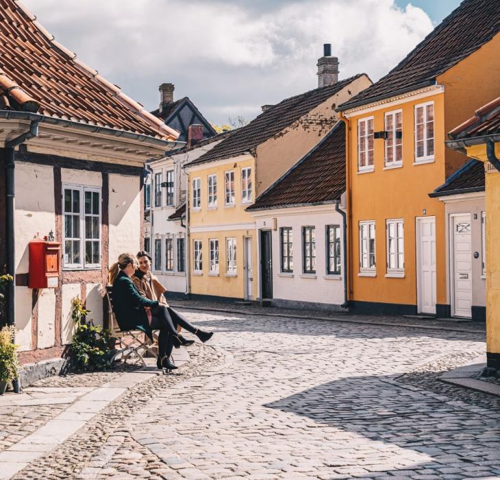 Zwei Freunde auf einer Bank in der Altstadt von Odense auf der dänischen Ostseeinsel Fünen